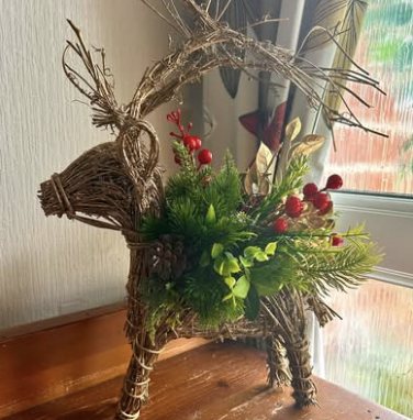 Twig reindeer dressed with greenery and red berries