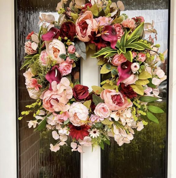 Wreath of pink and red peonies and burgundy calla lilies on a front door